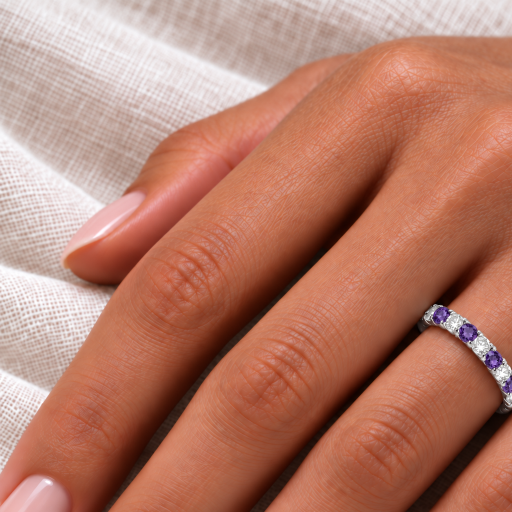 IR678LG lab amethyst and lab diamond eternity band in 14k white gold, close-up on left hand over ivory linen