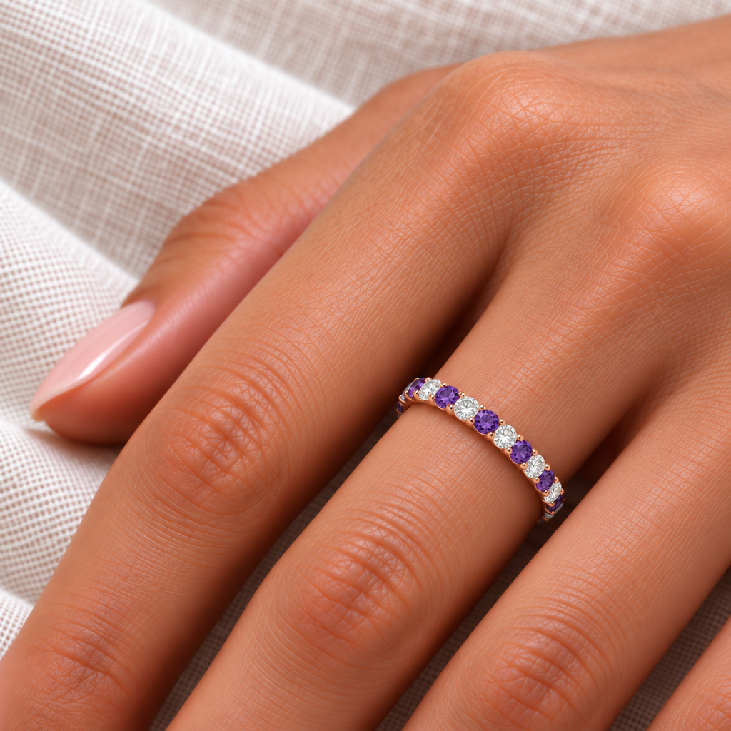 IR679LG lab amethyst and lab diamond eternity band in 14k rose gold, close-up on left hand over ivory linen