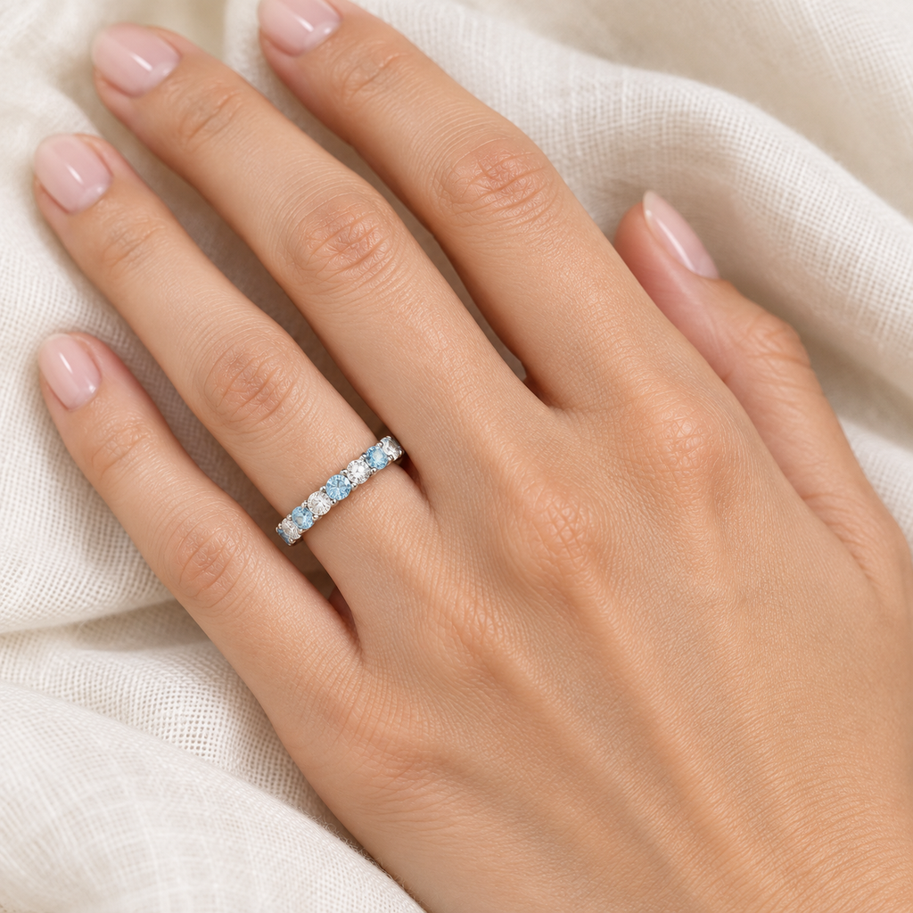 Aquamarine and diamond eternity ring worn on hand over soft ivory linen