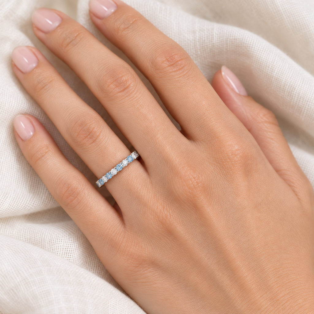 Aquamarine and diamond eternity ring in 14k white gold worn on hand at realistic 2.5 mm scale on ivory linen