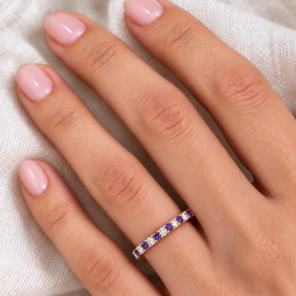 Lab purple amethyst and lab diamond eternity ring in 14k yellow gold, fine-scale ivory-linen hand close-up