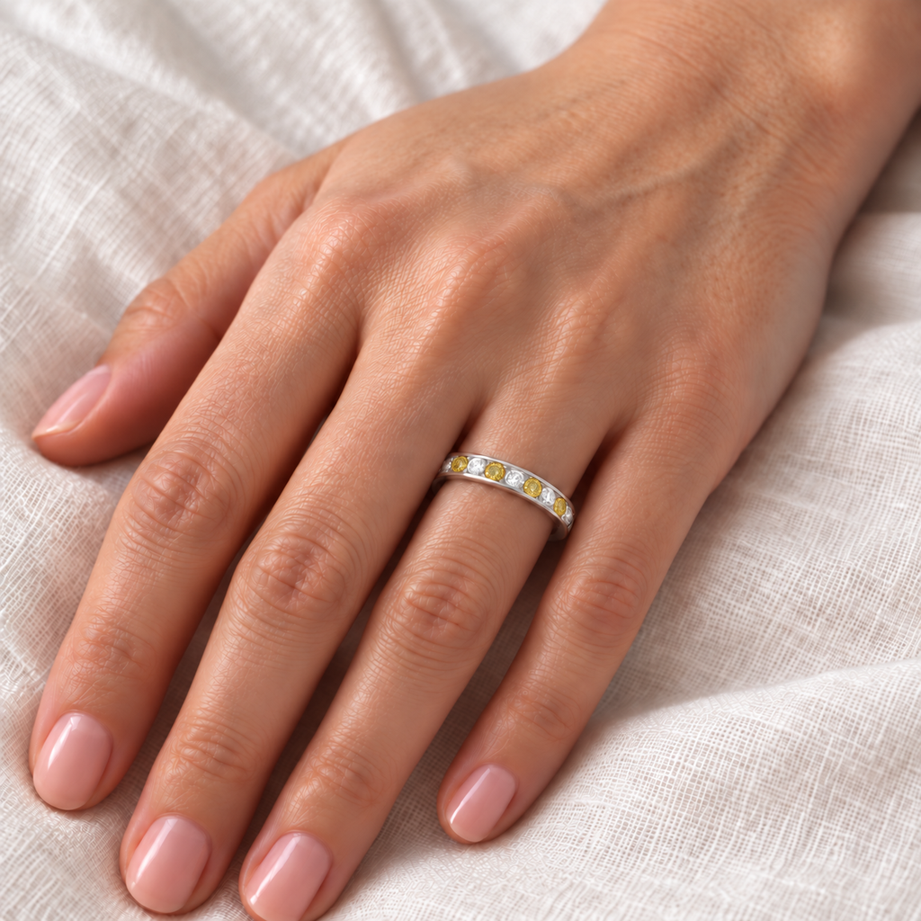 White and natural fancy yellow diamond channel-set ring in 14k white gold on left ring finger, linen close-up