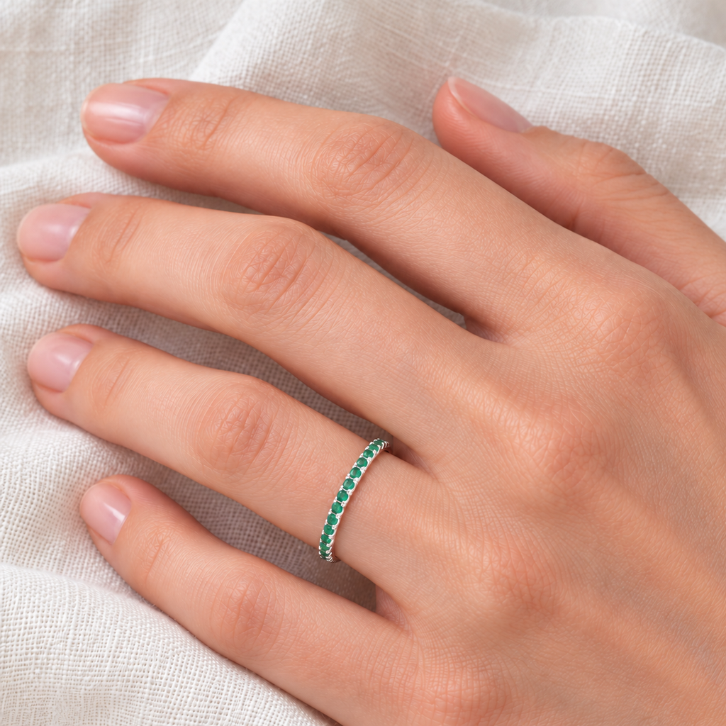 Fine-scale 2mm natural emerald half-eternity ring in high-polished 14k white gold on the left ring finger over ivory linen
