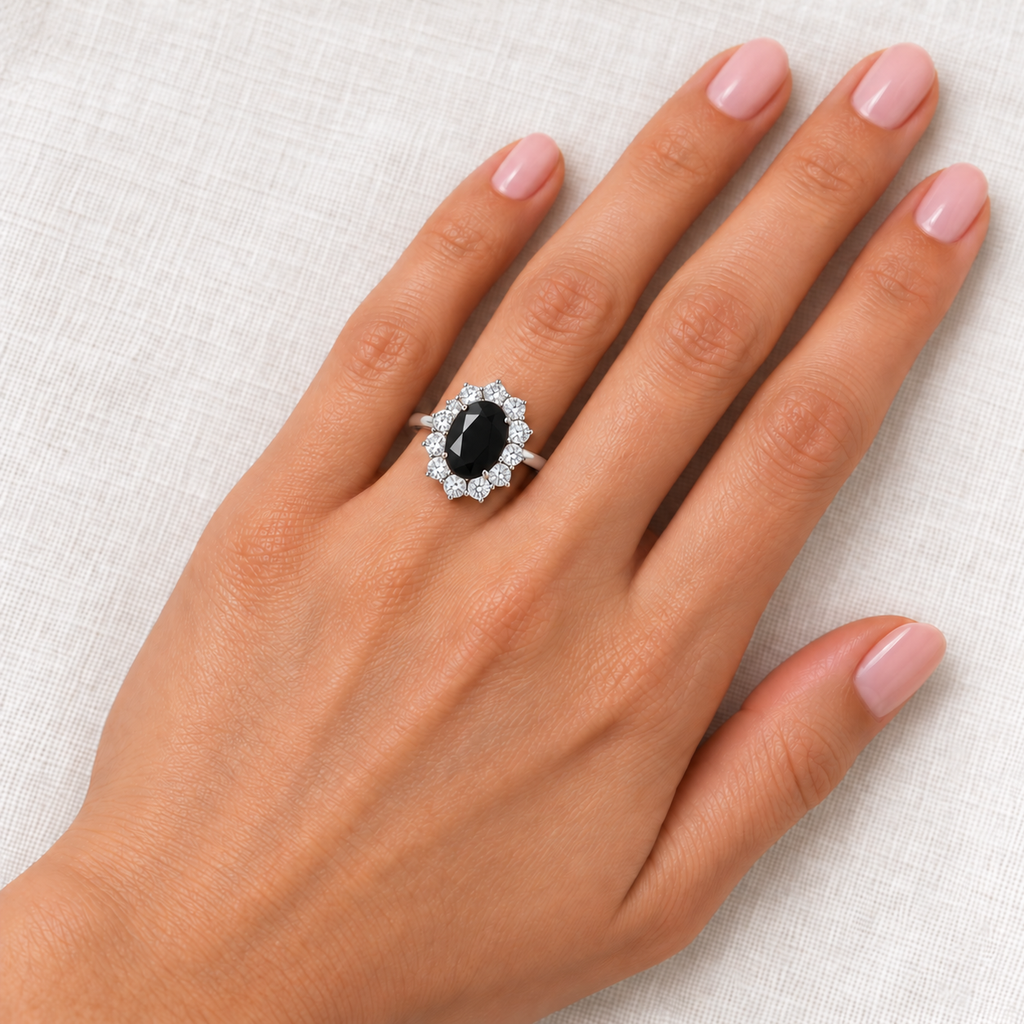 Natural 9x7mm faceted black onyx and 12-diamond halo Lady Diana ring in 18k white gold on left hand over ivory linen