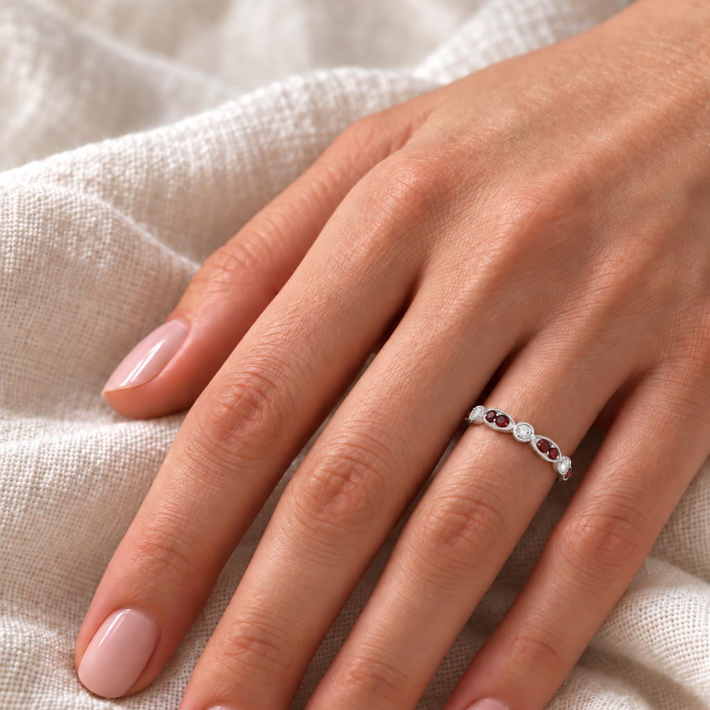 Marquise and dot natural garnet and diamond band in platinum on hand over ivory linen