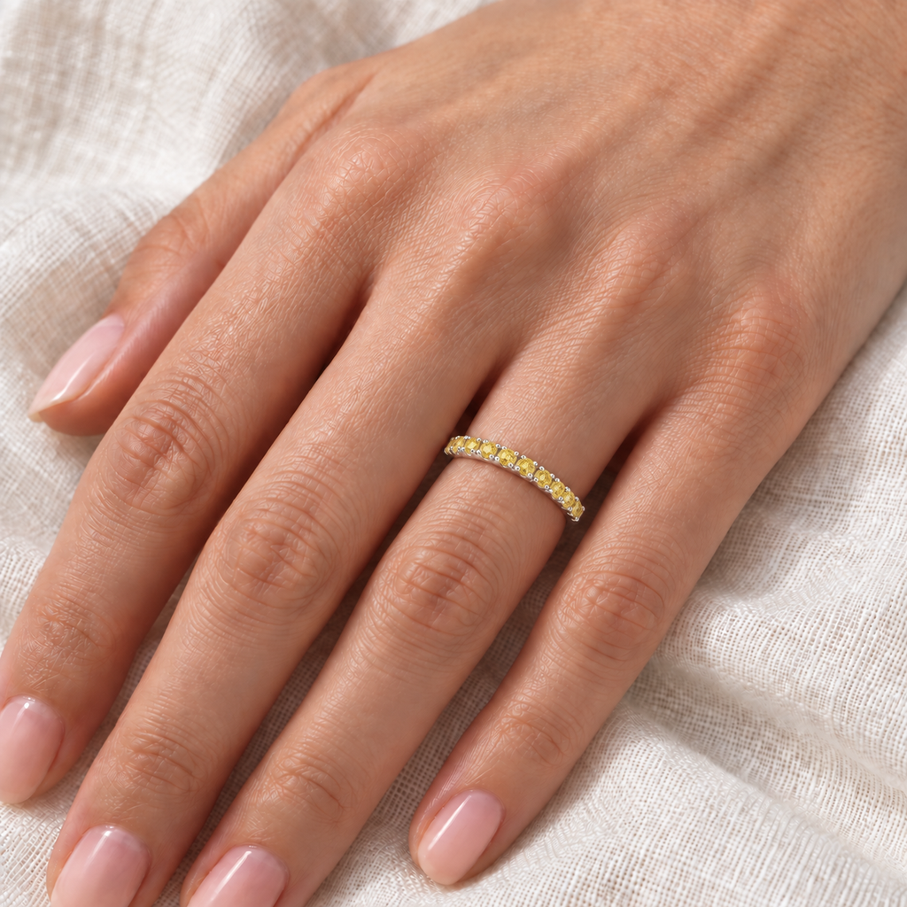 Yellow canary diamond white gold ring on left hand over ivory linen