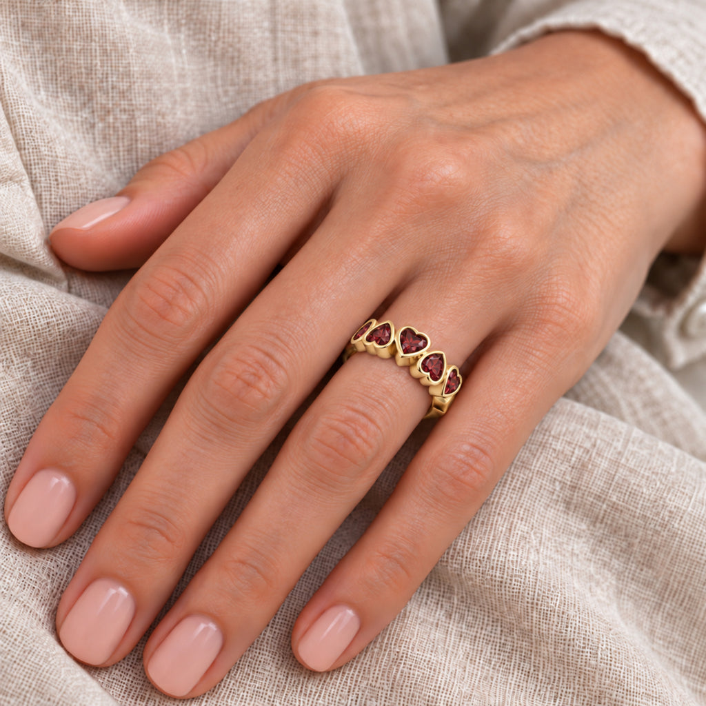 Five heart Mozambique garnet ring in YellowGold — close-up hand model view; approximate top 17 x 5.7 mm