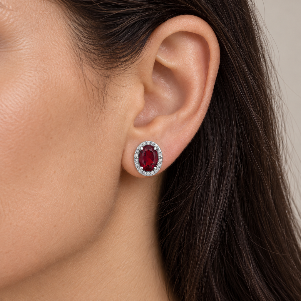 Oval ruby and diamond halo stud earrings 14K white gold, 7x5 mm center stones — close view; illustrative scale